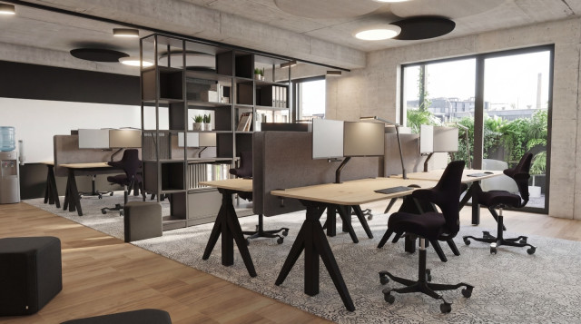 Modernes Büro im Greenhouse Senden mit Einzelarbeitsplätzen, Akustiktrennwänden, zentralem Metallregal und großen Fenstern mit Grünblick.