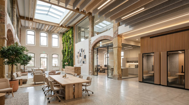 Mehrere Personen sitzen auf der Terasse eines Ladens vor dem Greenhouse, trinken Kaffee und unterhalten sich.