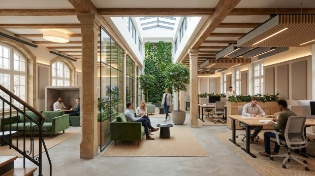 Drei Personen sitzen im Coworking Bereich des Greenhouse Senden an Tischen.
